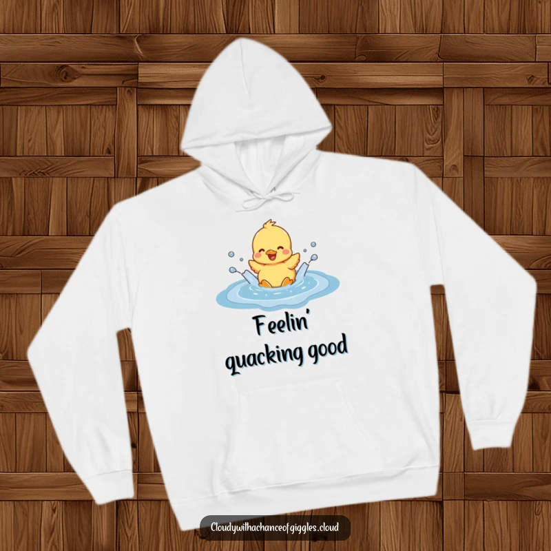 Funny duckling joyfully splashing in a cloud-shaped puddle, printed on a cozy hoodie, conveying a sense of lighthearted fun and comfort.
